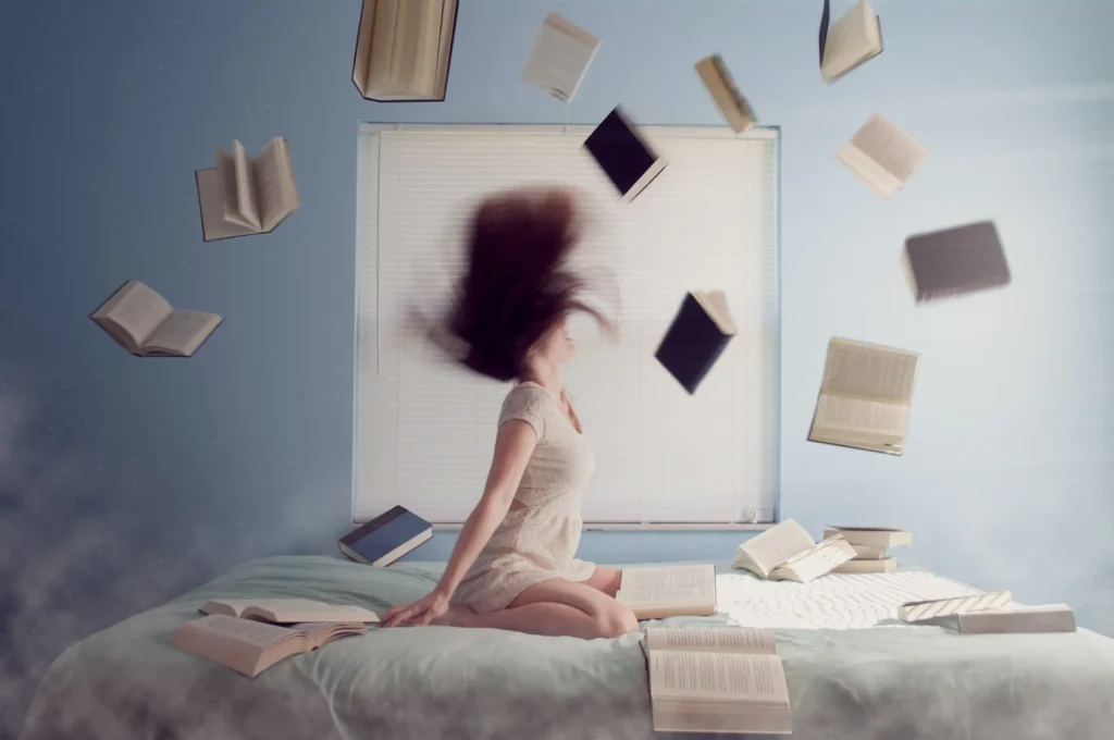 Offene Bücher schweben durch die Luft in einem hellen Raum, während eine Person auf einem Bett sitzt – symbolisiert kreatives Lernen und Wissensvielfalt.