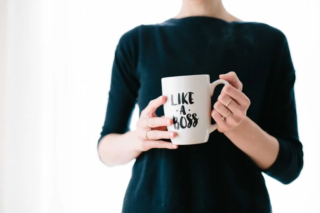 Person hält weiße Tasse mit der Aufschrift ‚LIKE A BOSS‘ – Symbol für Leadership und Selbstbewusstsein.