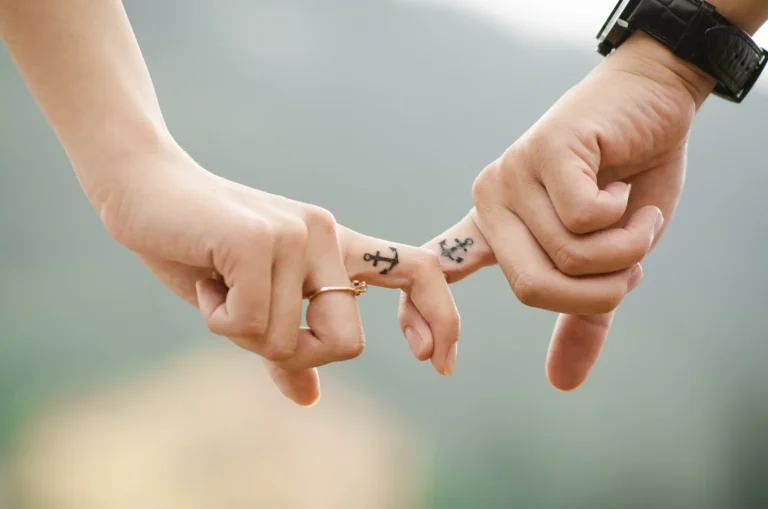 Zwei Hände, die Zeigefinger sind eingehackt und jetzt hat einen Anker darauf tattowiert.