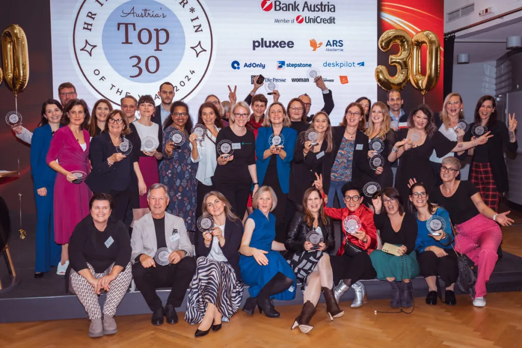 Gruppenfoto der Preisträger:innen beim HR Influencer:innen Award mit Trophäen vor einer Bühne mit Top-30-Logo und Sponsoren