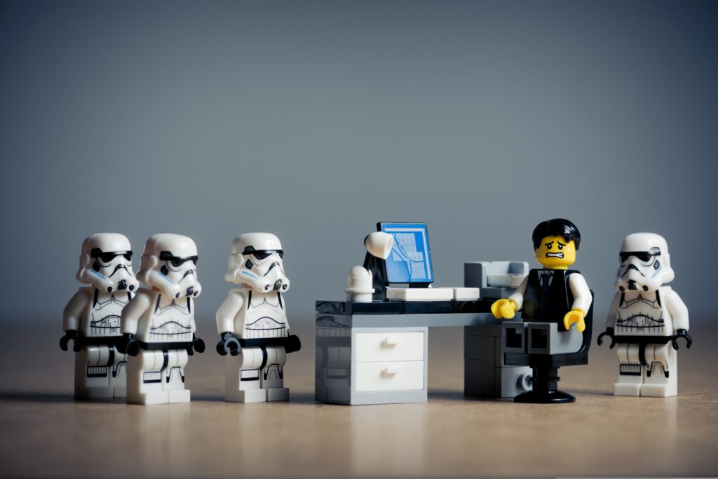 Standardisierte Bewerbungsprozesse im Recruiting symbolisch dargestellt mit Lego‑Figuren vor einem Schreibtisch